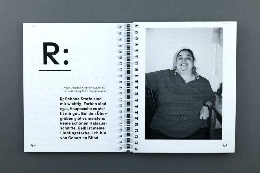 Foto von einem aufgeschlagenem Buch mit Ringelbindung, Schwarzdruck und Braille übereinander, rechte Seite Text, linke Seite Portrait einer Person